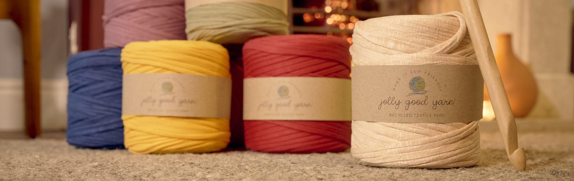 Collection of different coloured T-Shirt yarns with crochet hook in front of fireplace