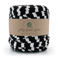 A skein of jolly good yarn made from recycled textile yarn, featuring a black and white checkerboard pattern wrapped in a brown kraft paper label. The brand 'jolly good yarn' is clearly visible on the label.