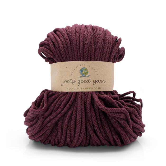 A skein of Jolly Good Yarn braided cord in a deep burgundy color, wrapped with a kraft paper label that reads 'jolly good yarn' and 'recycled braided cord'.