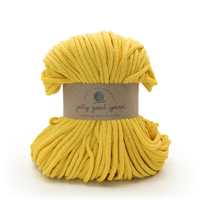 A skein of bright yellow braided cord yarn wrapped with a brown paper label that reads 'jelly good yarn' and 'recycled braided cord', photographed on a clean white background.