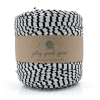 A skein of black and white striped recycled textile yarn wrapped in a brown kraft paper band labeled 'jolly good yarn'.