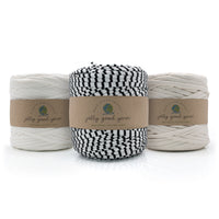 Three skeins of twisted cotton yarn from Jelly Good Yarn arranged in a row. The left and right skeins are off-white/cream, and the center skein is black and white striped.